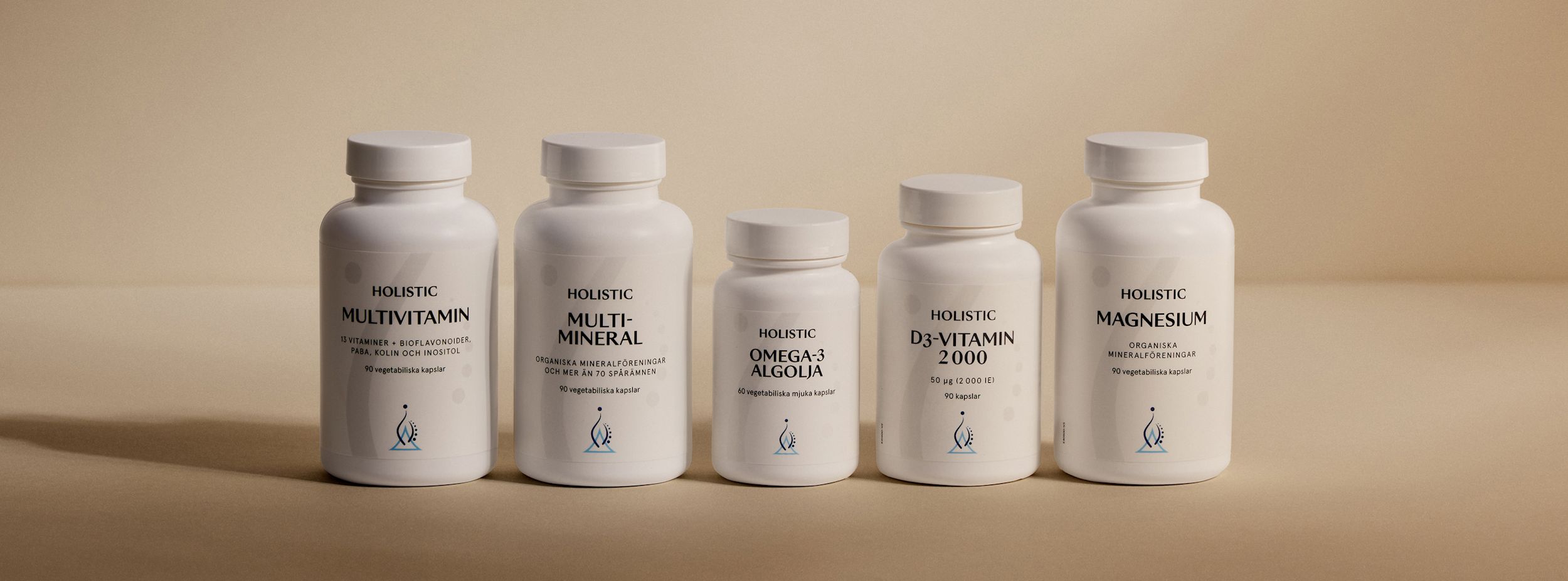 Fem vita burkar med Holistic kosttillskott: Multivitamin, Multimineral, Omega-3 Algolja, D3-Vitamin 2000 och Magnesium, står på rad.