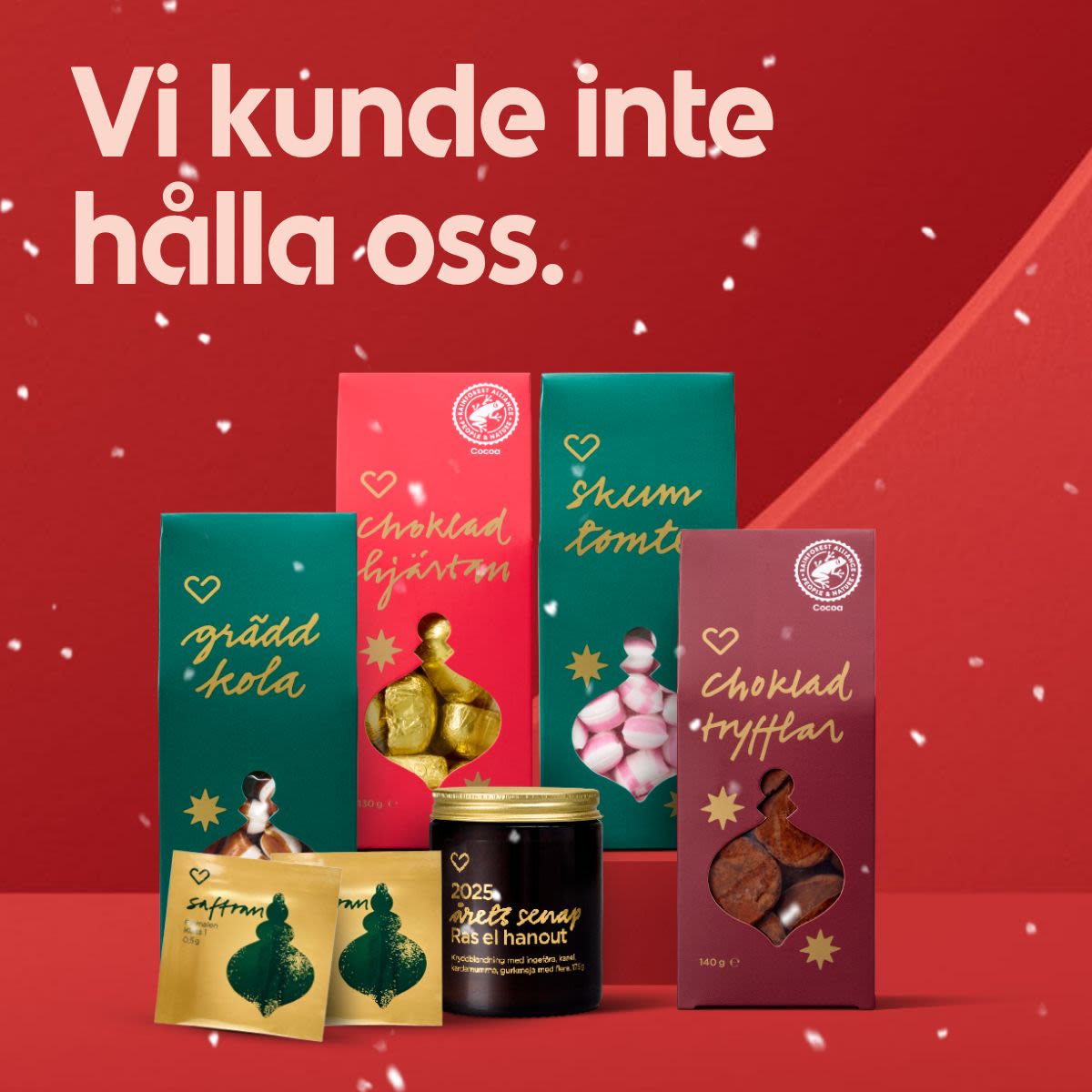 Flera förpackningar med julgodis och senap står på rött underlag med röd bakgrund och texten "Vi kunde inte hålla oss." snö faller lätt.