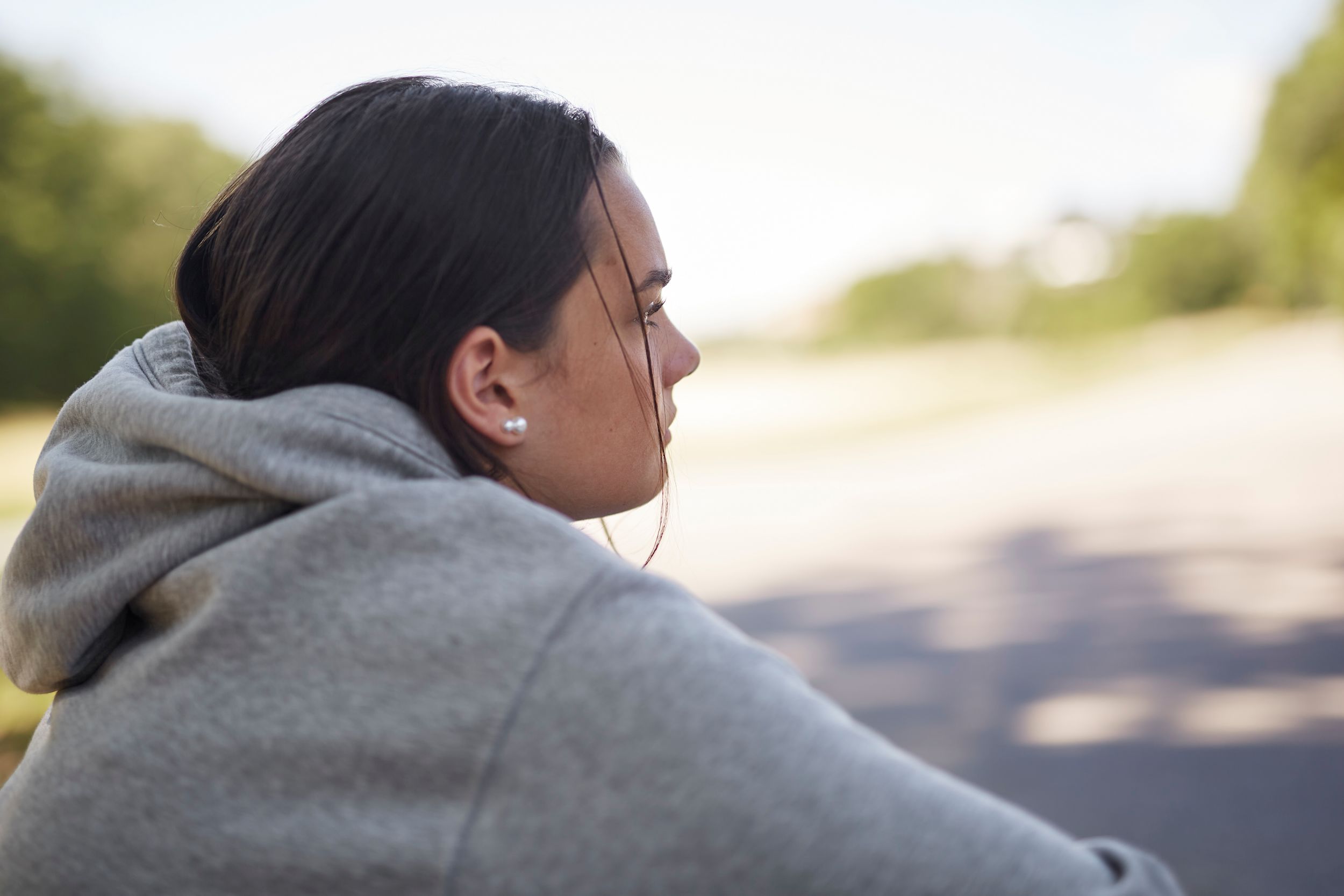 Tonårstjej sitter utomhus och tittar bort.