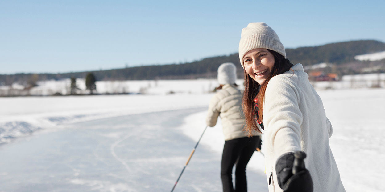 Kvinna är ute på isen och kollar leendes bak mot kameran.